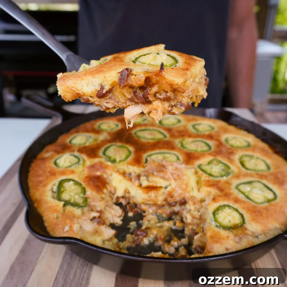 A second, equally enticing view of the BBQ Chicken Cornbread Casserole, with a generous portion removed, clearly highlighting the tender, saucy chicken and bean filling nestled beneath the impeccably golden cornbread topping.