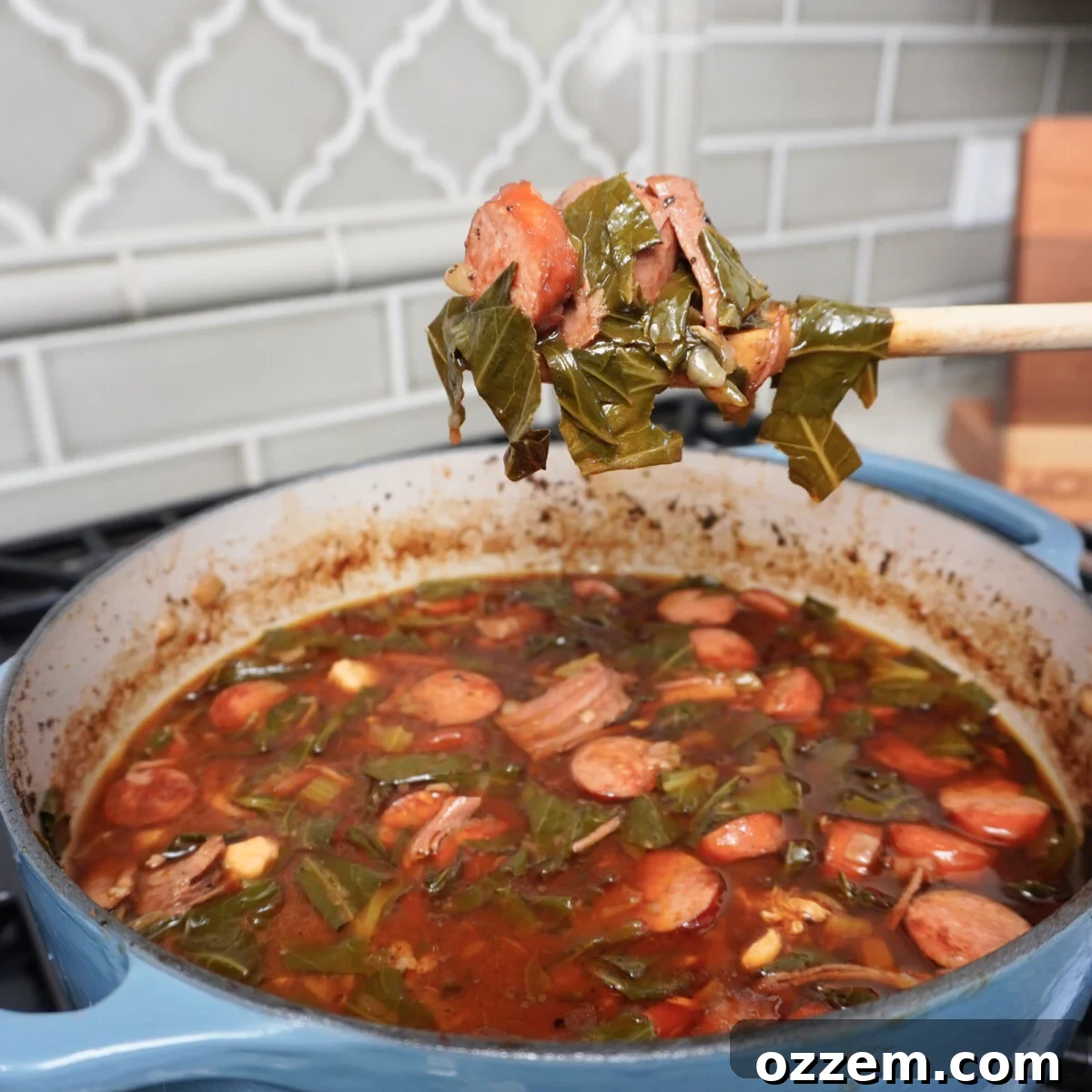 Collard Greens Cajun Gumbo scooped up on a wooden spoon over a pot.