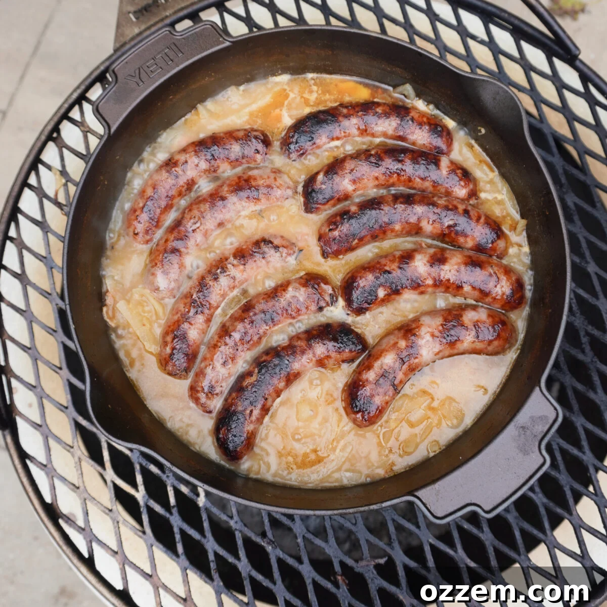 The best grilled beer brats simmering in a Dutch oven over an open fire.