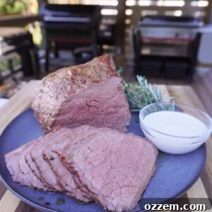 Smoked bottom round roast placed and sliced with a creamy garlic dipping sauce on the side.