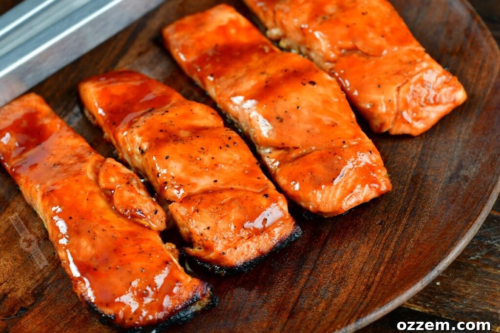 Caramelized Maple BBQ Grilled Salmon 3 Four glazed grilled salmon fillets arranged beautifully on a rustic wooden plate