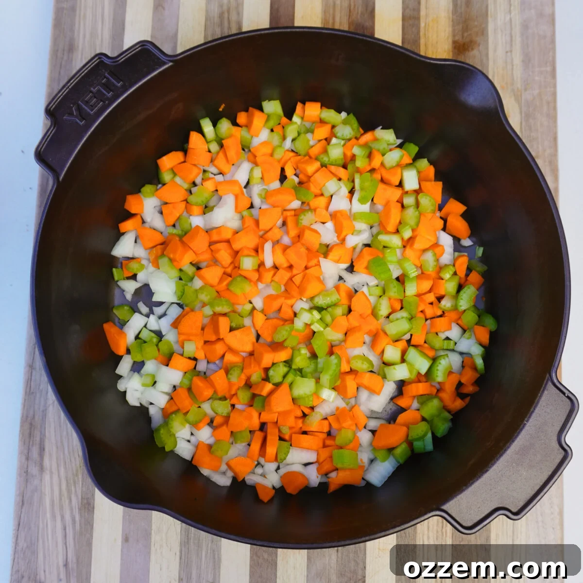 Diced carrots, celery, and onion in a cast iron skillet for soffritto.