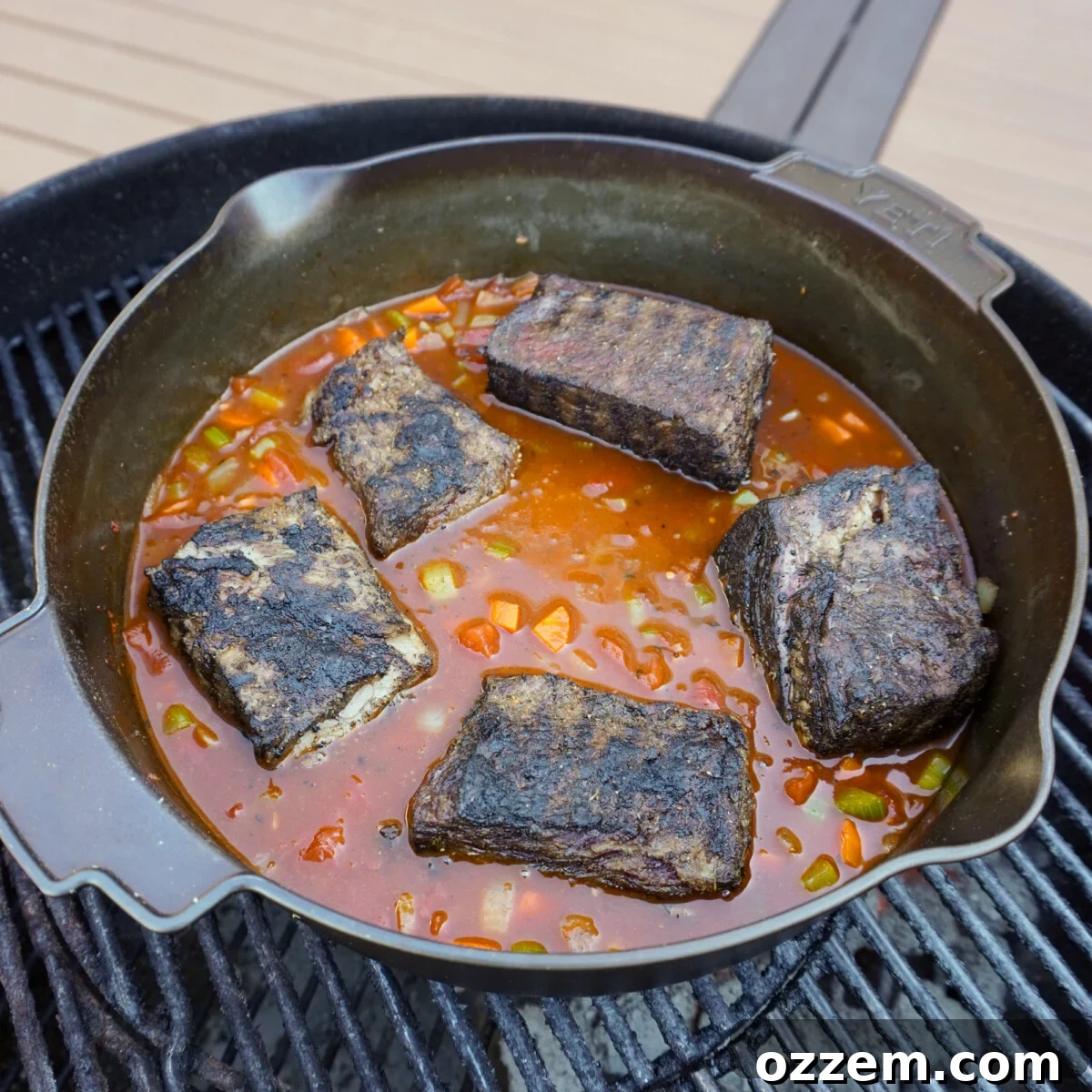 Ragu broth with grilled short ribs simmering in a cast iron skillet.