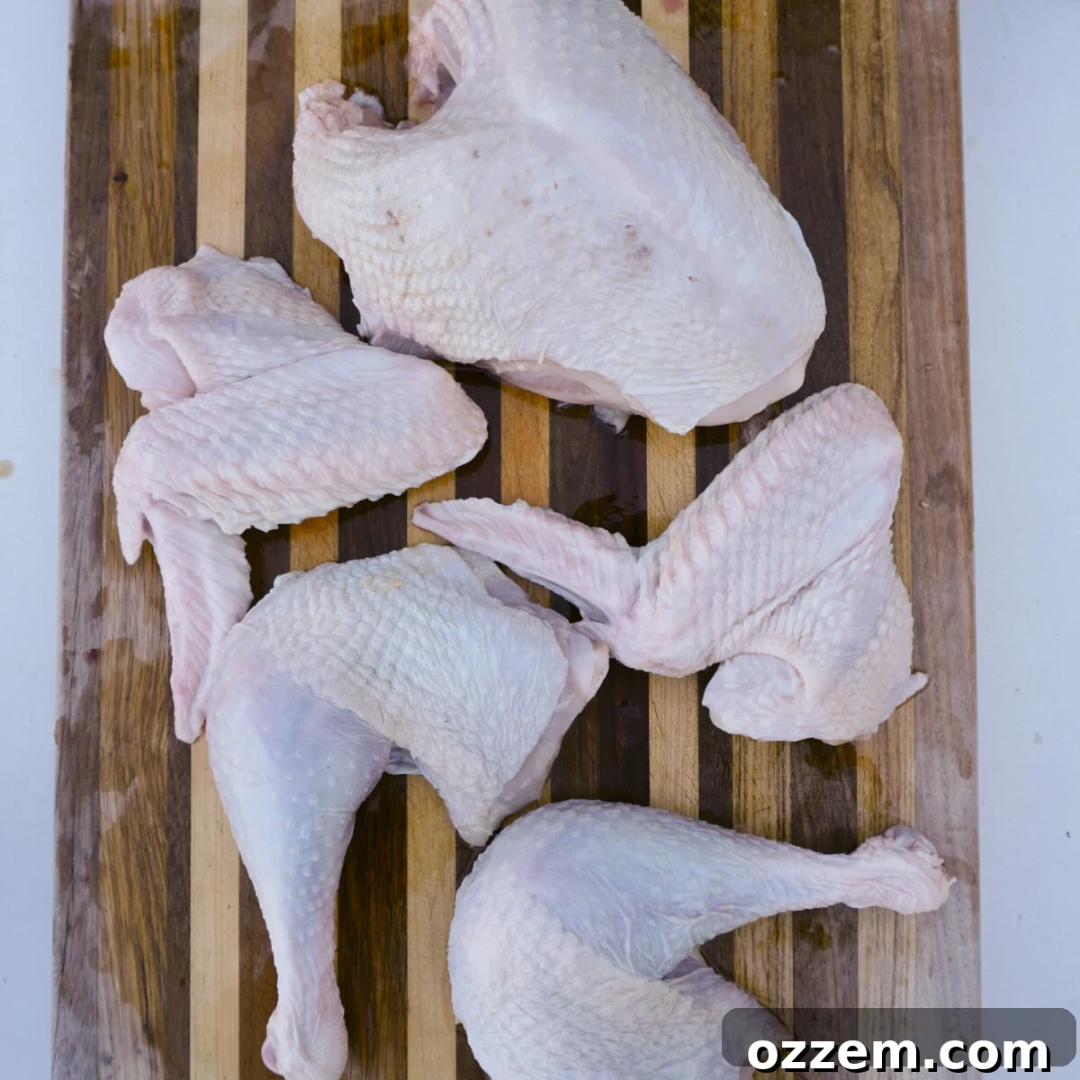 A whole turkey expertly separated into distinct drumsticks with thighs, breast, and wings, ready for brining and grilling.