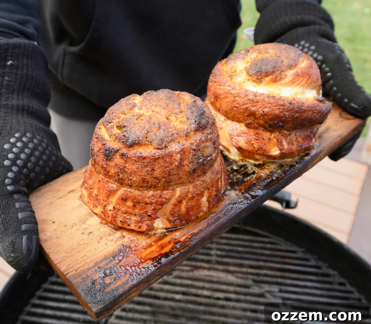 Grilled Jalapeno Popper Salmon Pinwheels on a cedar plank over a charcoal grill.