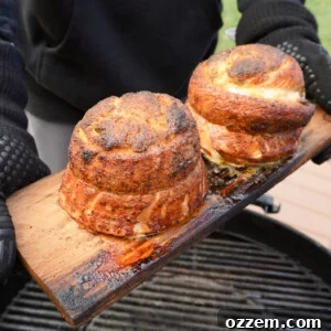 Grilled Jalapeno Popper Salmon Pinwheels on a cedar plank over a charcoal grill.
