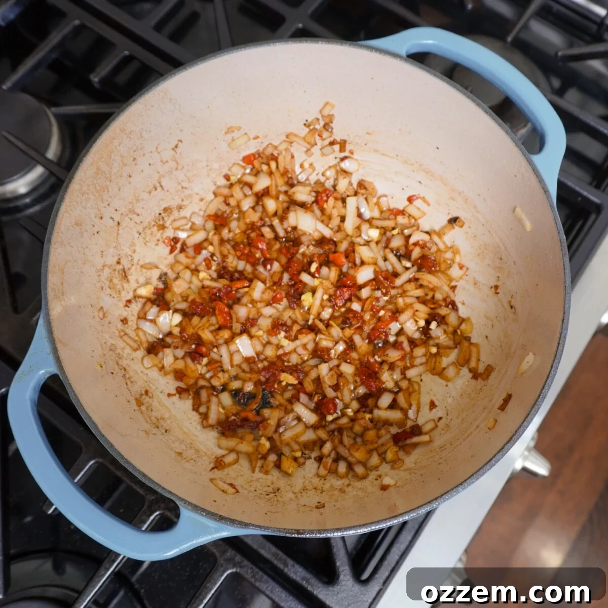 Diced onions, sun-dried tomatoes, and garlic sautéing in a dutch oven, releasing rich aromatics.