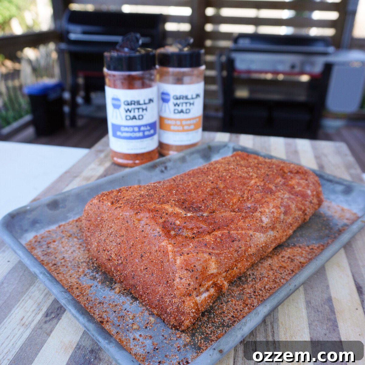 seasoned pork on a tray with seasoning bottles in the background.