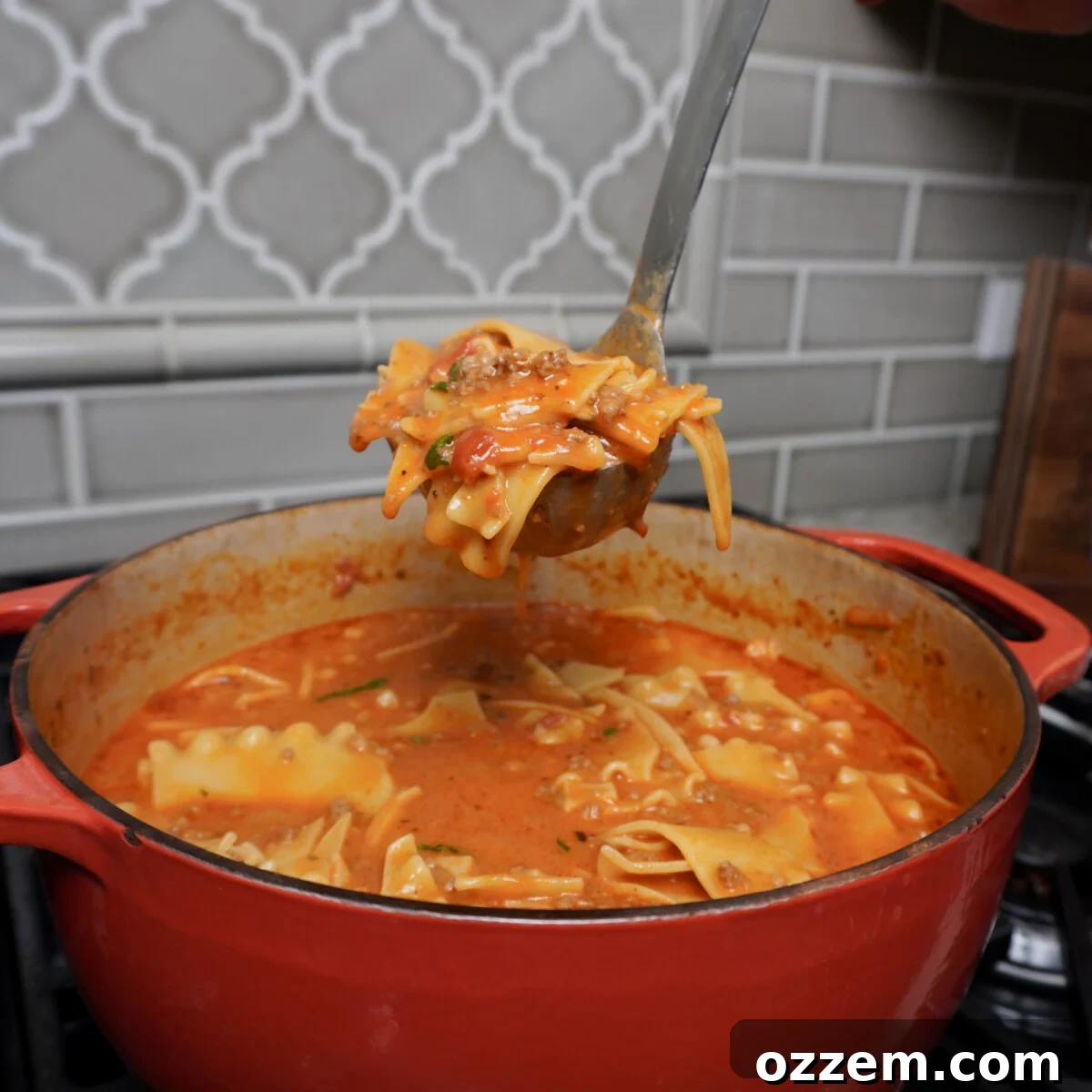 Ladle full of Lasagna soup over a dutch oven.