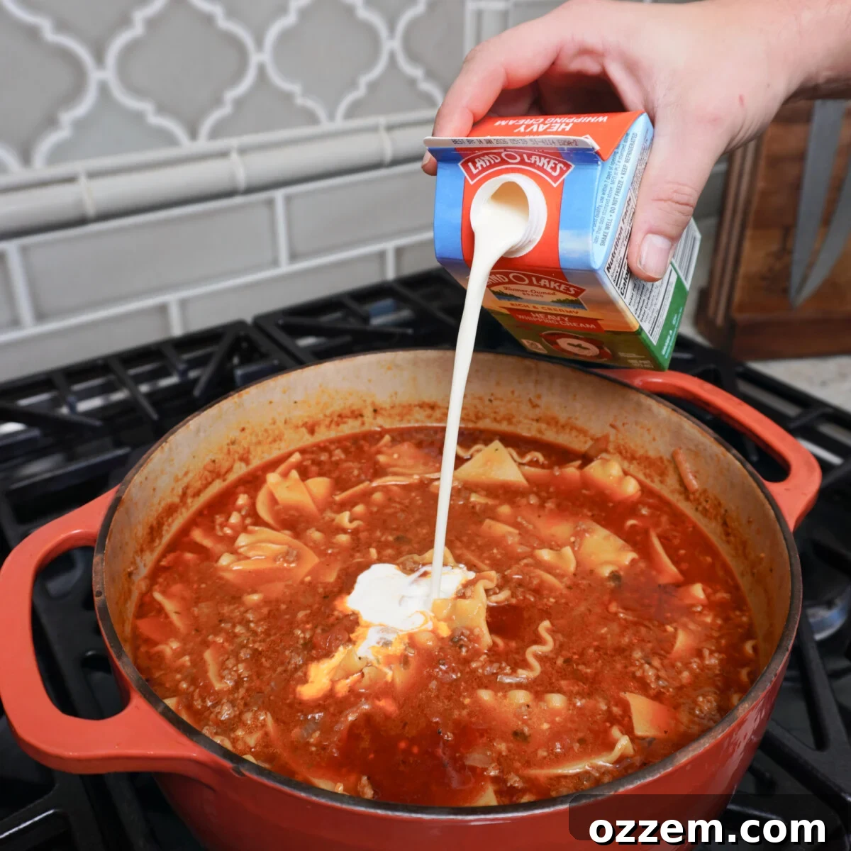 adding heavy cream into the lasagna soup.
