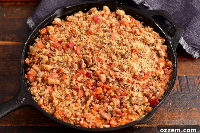 Close-up of the sweet potato casserole filling in a skillet, topped generously with the pecan crunch mixture, ready for smoking.