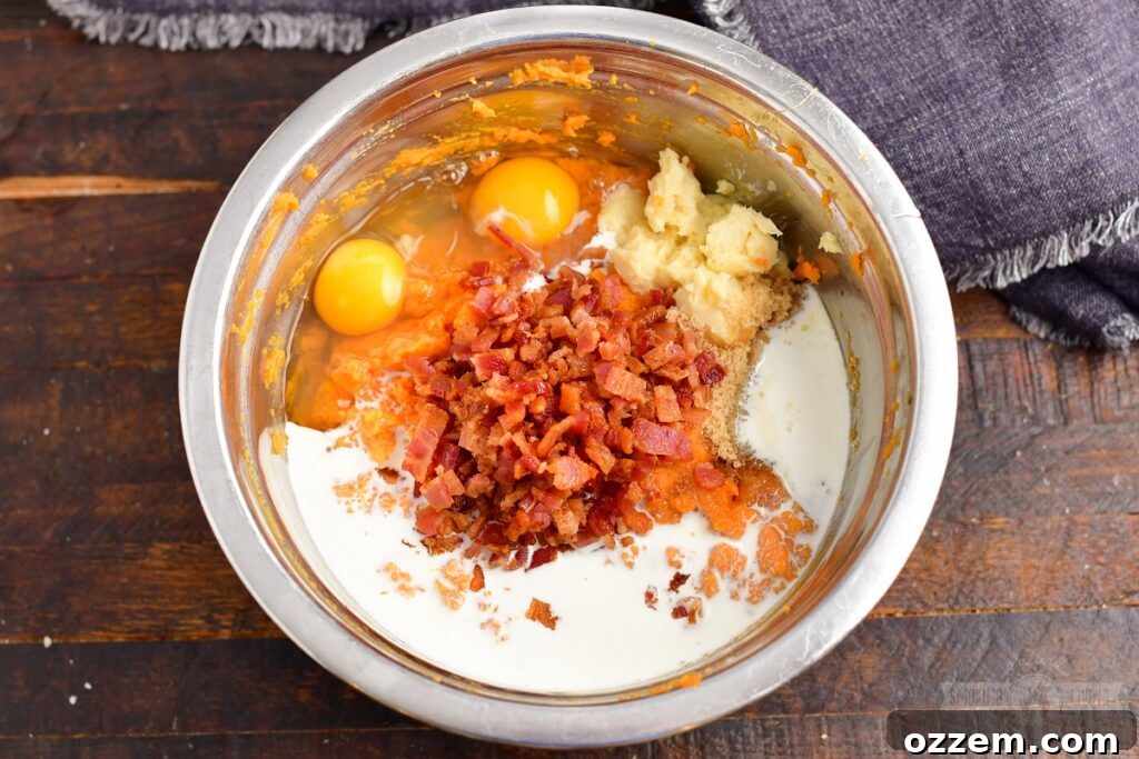 Adding butter and other ingredients to the mashed sweet potatoes for the casserole filling.