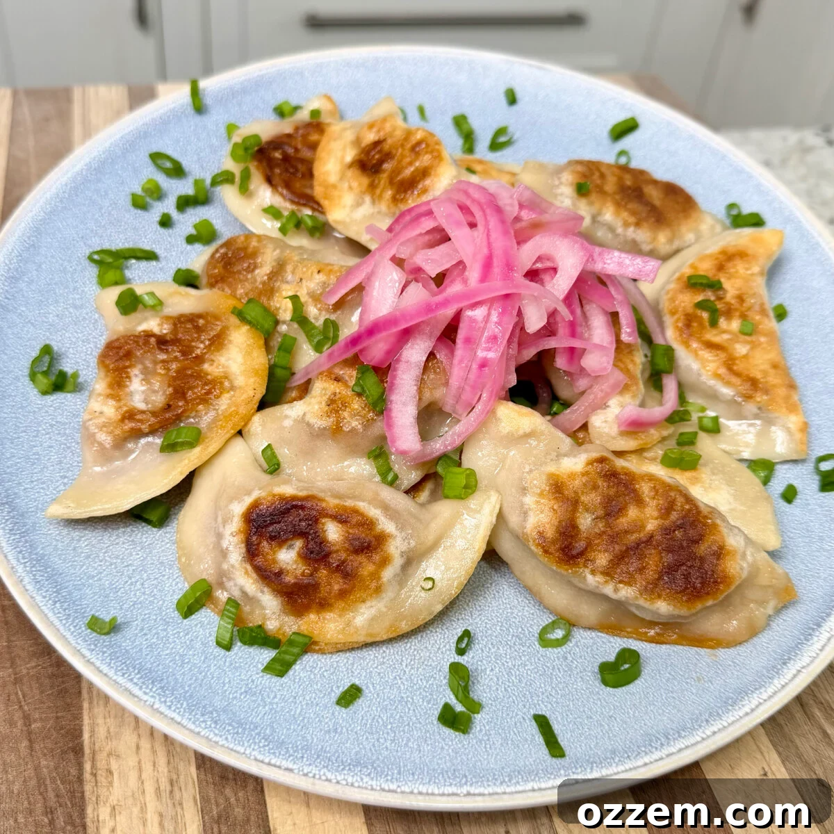 BBQ Pulled Pork Pierogi 2 Pulled pork pierogi placed with pickled red onion on top, garnished with fresh herbs.