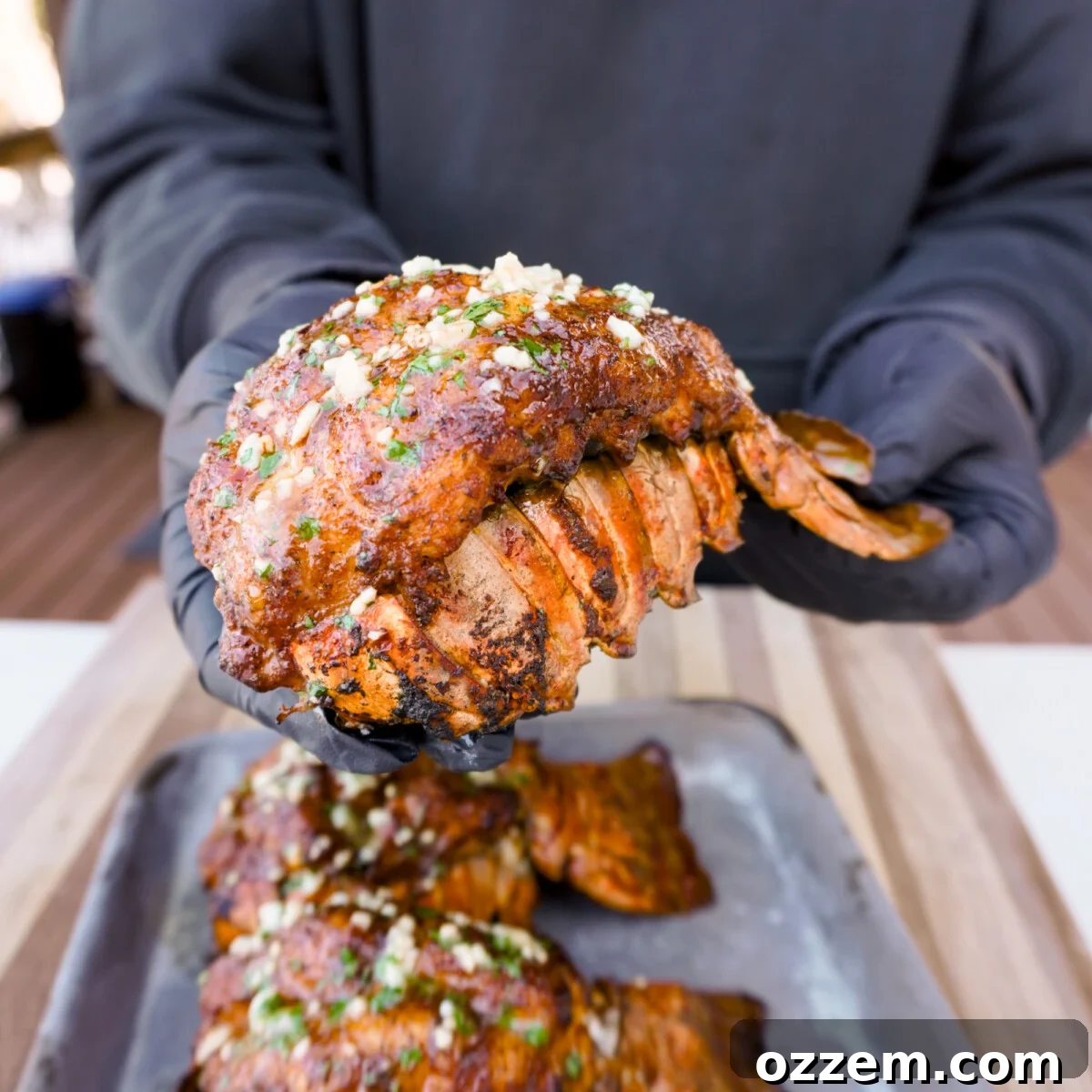 Smoked Cajun lobster tail presented in hands, showcasing its delicious appeal.