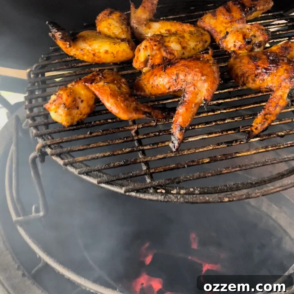 Chicken wings grilling over charcoal on an elevated grate, showing beautiful char marks.