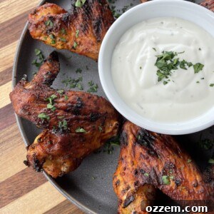 Plated crispy grilled hot wings with a side of dipping sauce.
