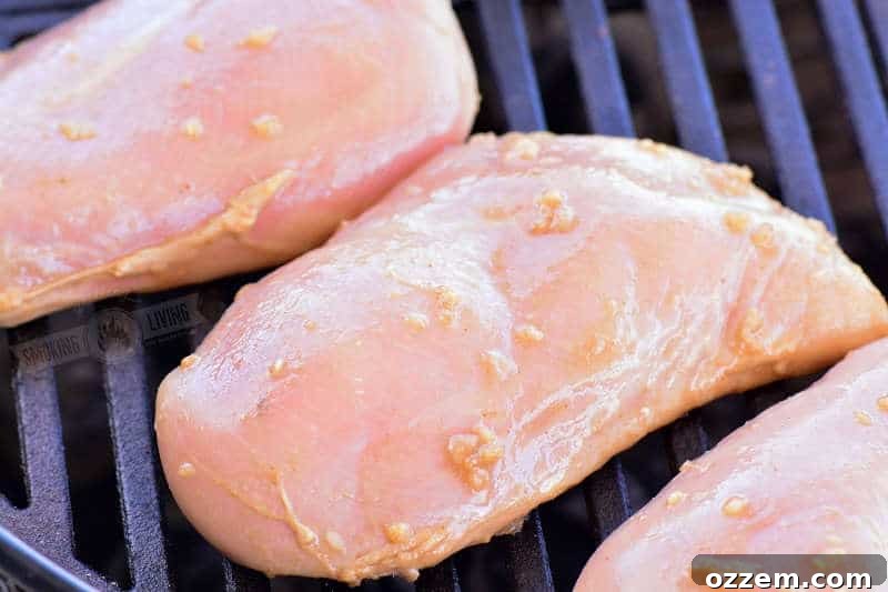 Bourbon Glazed Grilled Chicken 4 Raw, marinated chicken breasts laid out on a grill grate, ready for cooking.