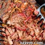 Top-down view of perfectly smoked pulled beef chuck being shredded in a cast iron skillet