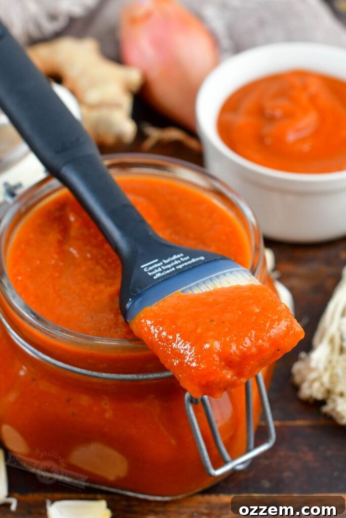 Dipped brush in BBQ sauce over the jar of homemade peach BBQ sauce