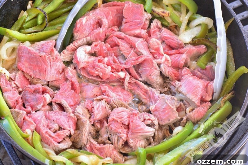steak, onions, and peppers in the skillet