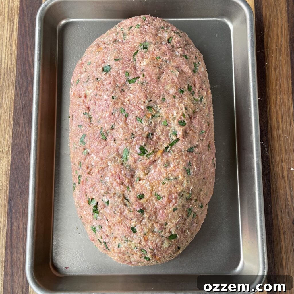Meatloaf shaped into a loaf on a sheet pan, ready for the grill