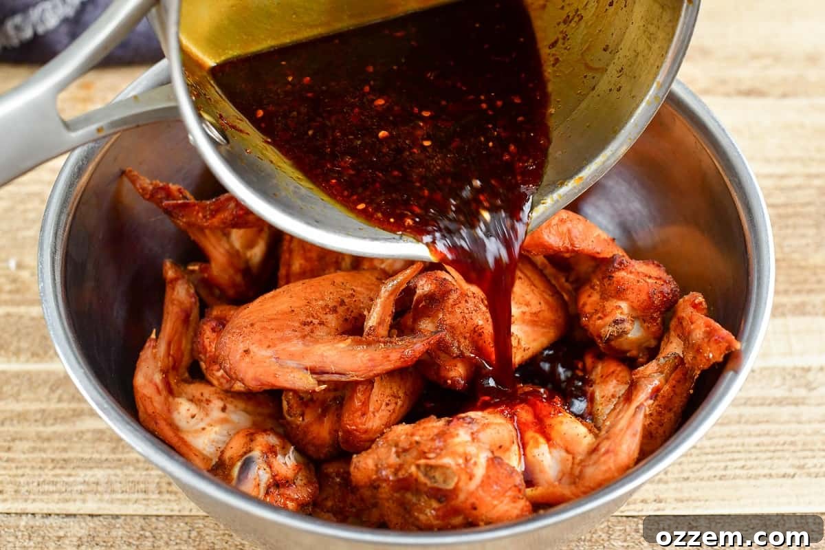 adding glaze to the bowl with smoked wings in it