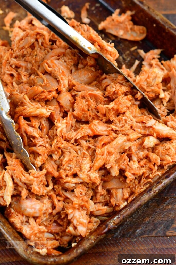 Close-up of sauced pulled chicken in a pan, ready to serve.