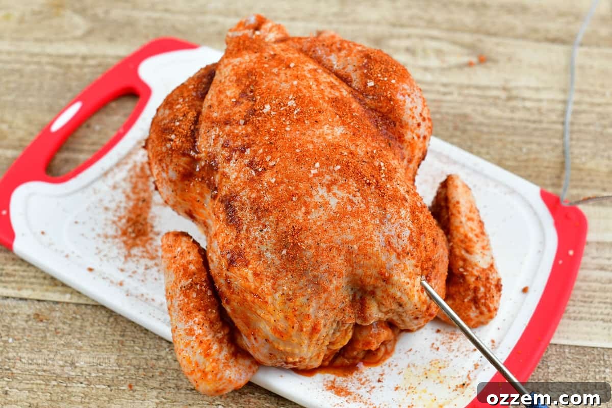 Seasoned whole chicken on a cutting board, ready for the smoker.