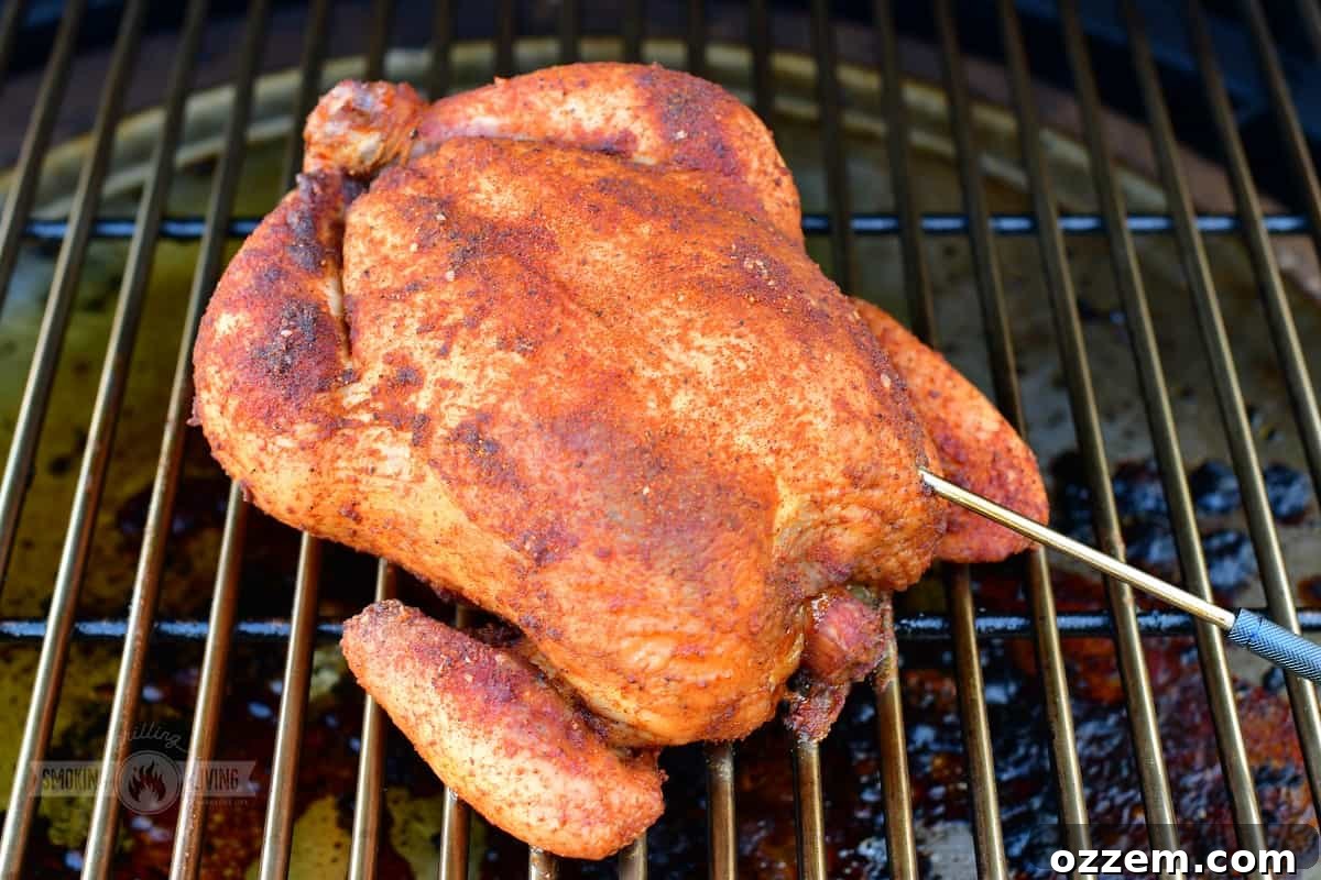 Whole chicken smoking on a grate with a digital thermometer inserted.