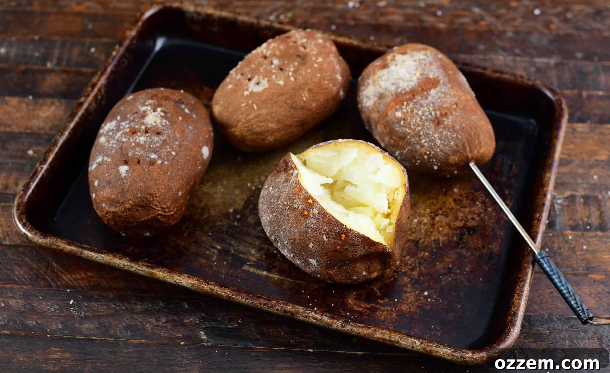 Cooked smoked baked potatoes on a rack, one with a temperature probe still inserted.