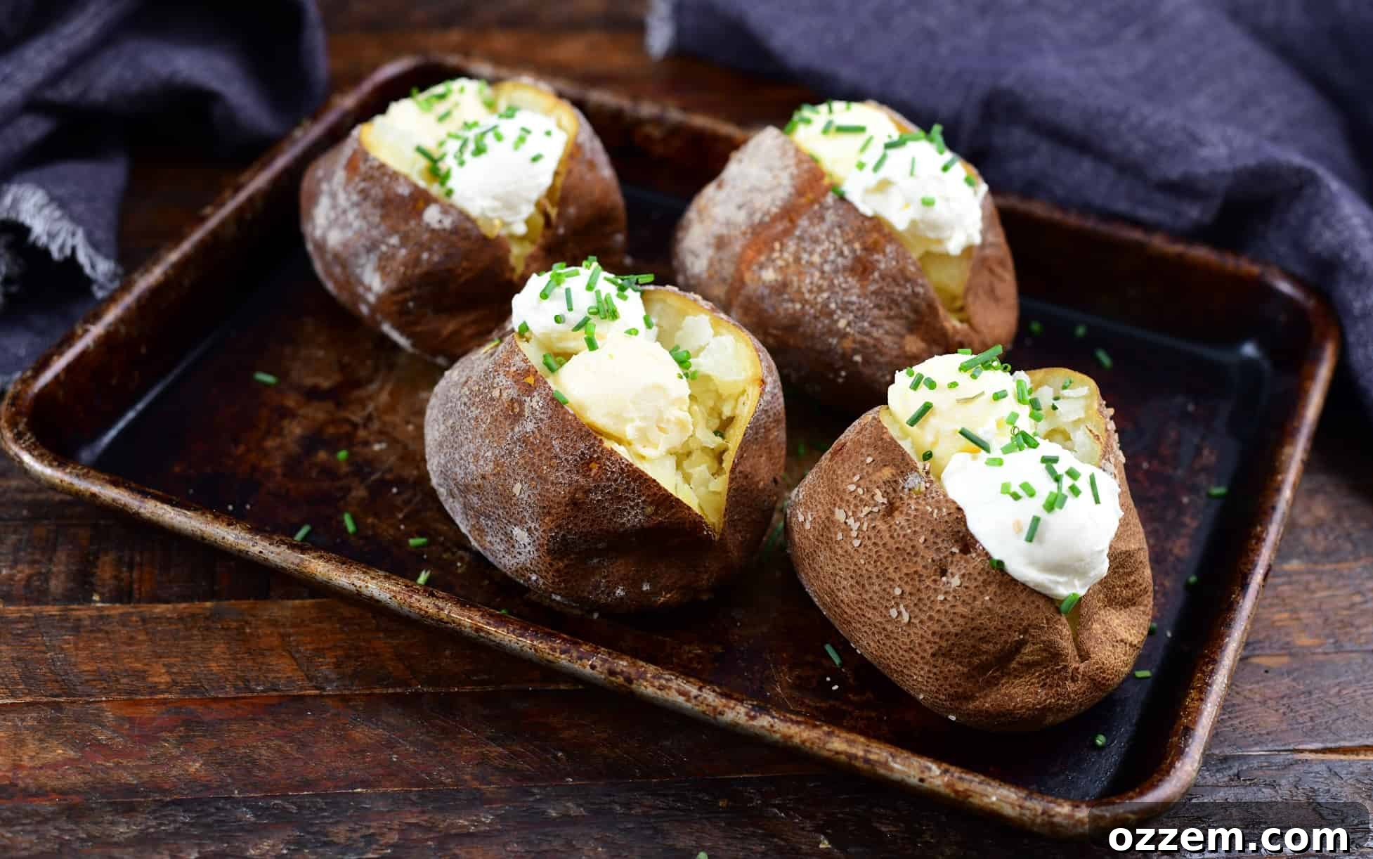 Smoked baked potatoes topped with butter, sour cream, and chives, ready to be served.