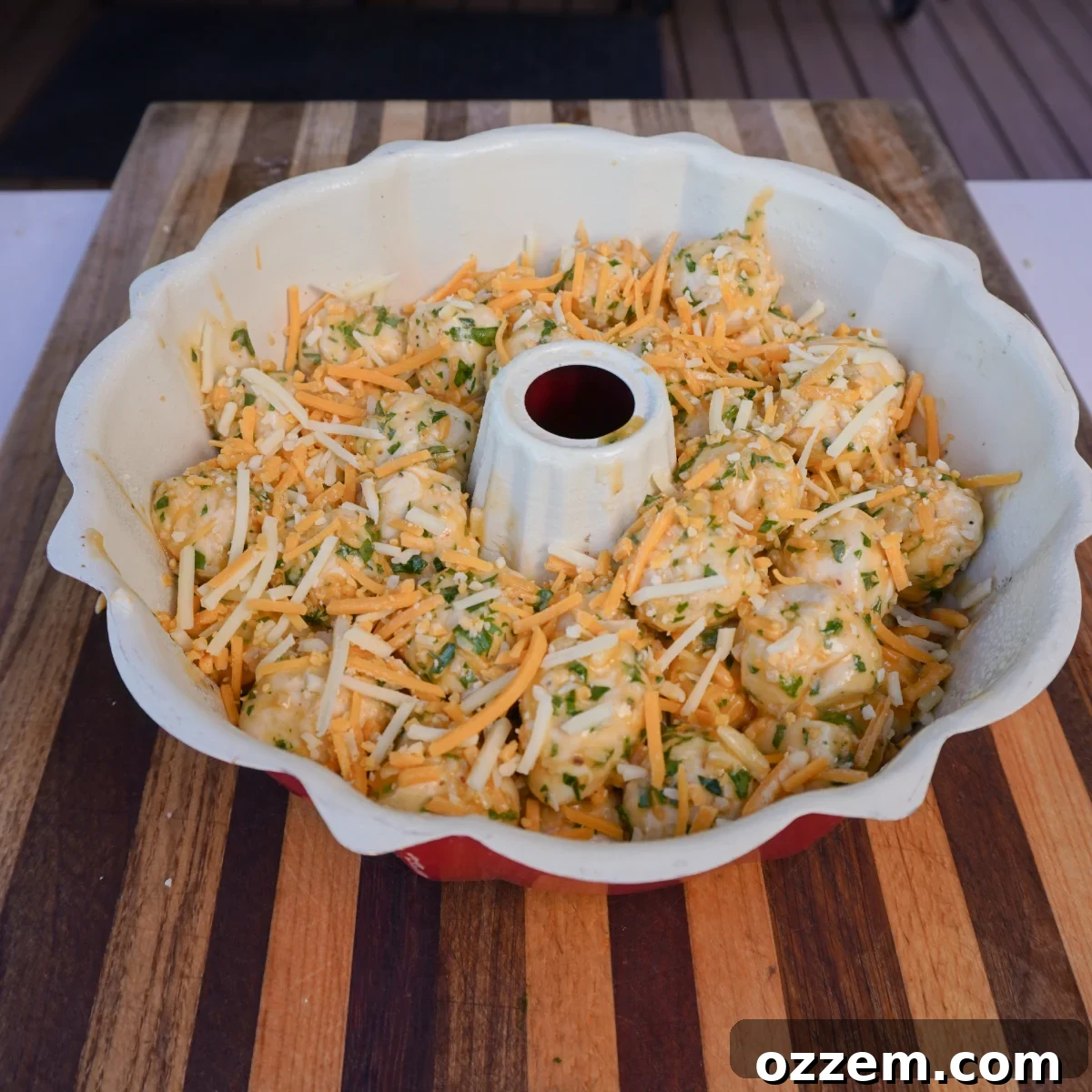 Bowl of rich garlic and herb butter mixture with shredded cheese.