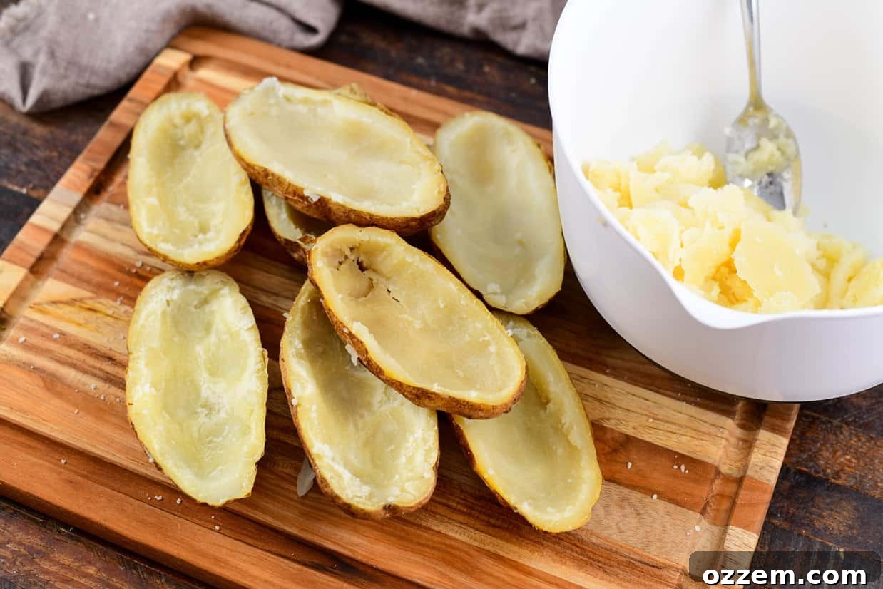Smoky Creamy Twice Baked Potatoes 8 potato shells on a cutting board with potato meat in a white bowl