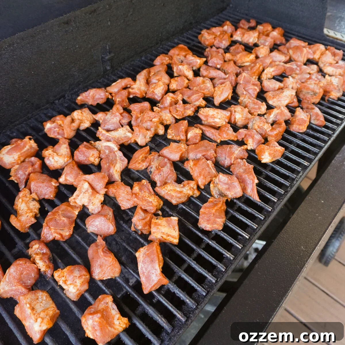Succulent Pork Poppers 6 Seasoned pork shoulder bites arranged on smoker grates, smoking.