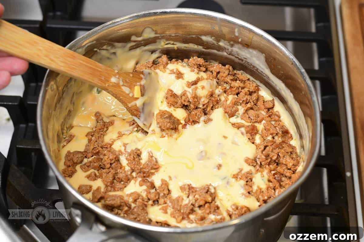 Campfire Queso Dip 11 Smoked chorizo being thoroughly mixed into the rich and creamy cheese dip, ensuring even distribution.