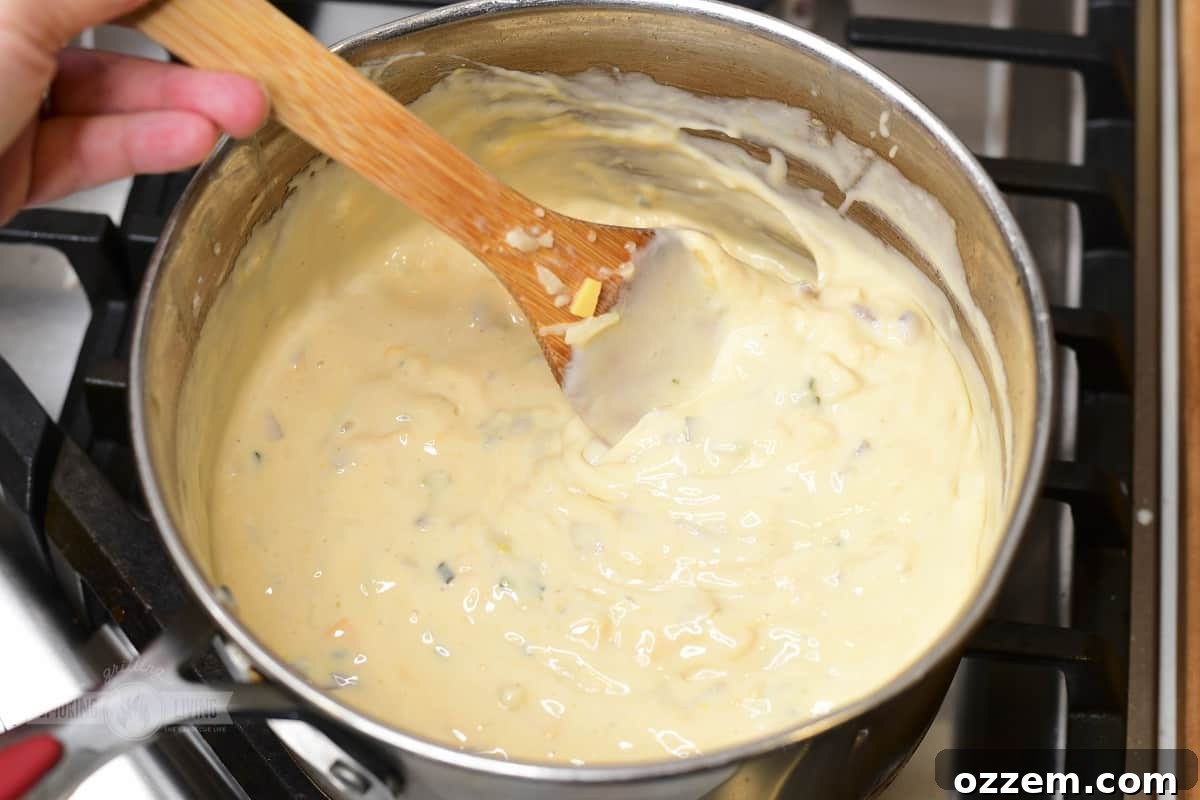 Campfire Queso Dip 12 Cheese and veggies cooking together in a pot, creating a creamy base before the final smoke.