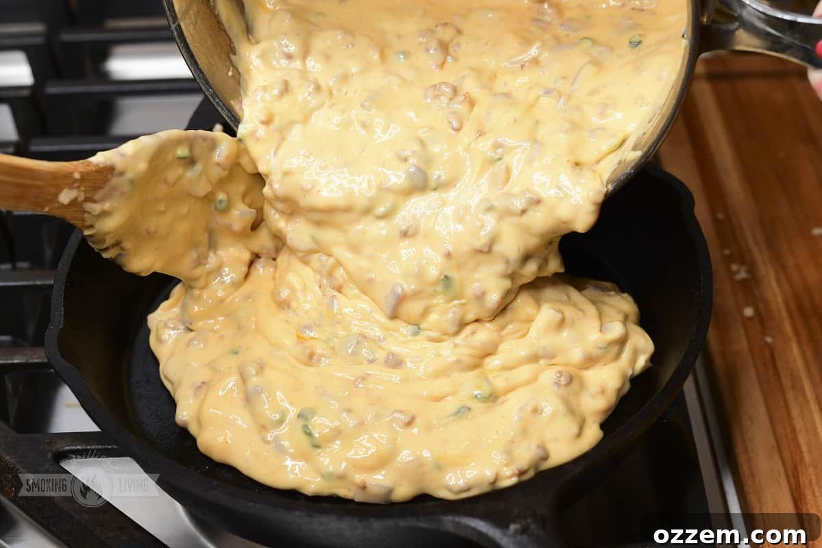 Campfire Queso Dip 13 Cooked queso dip being poured into a cast iron skillet, ready for its final smoke.