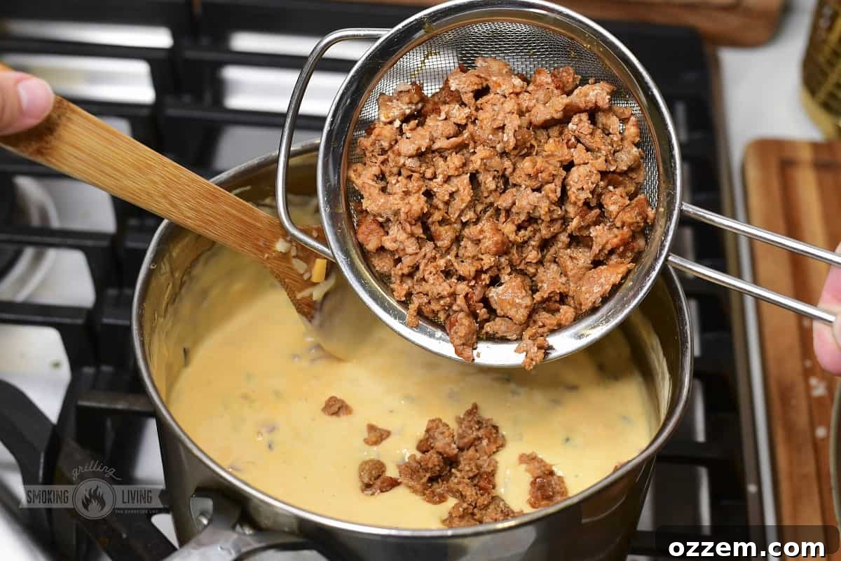 Campfire Queso Dip 10 Smoked chorizo being poured into the creamy queso dip, ready to be mixed in.