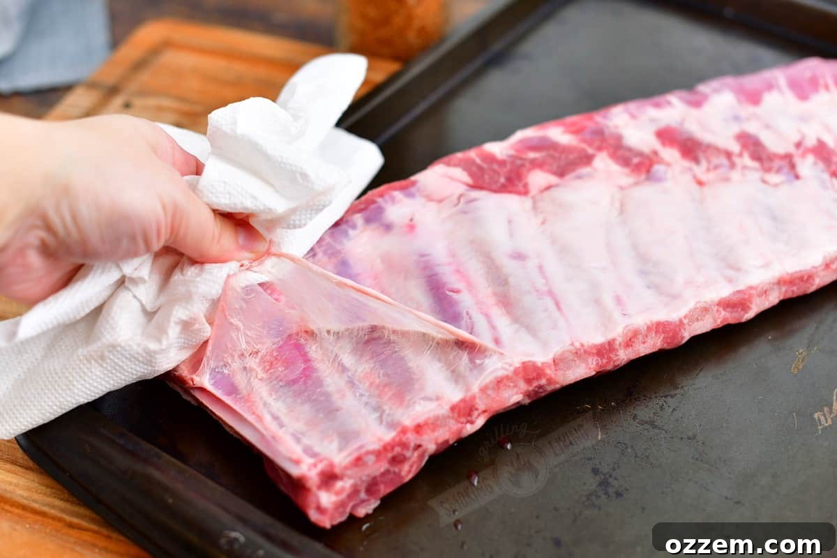 carefully pulling off a membrane off the back of rack of ribs