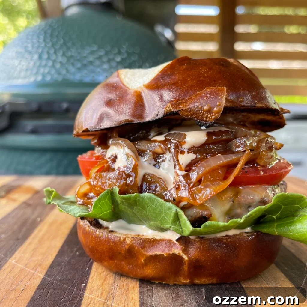 Venison Beef Burger, perfectly cooked with melted cheese, lettuce, tomato, and caramelized onions on a pretzel bun.