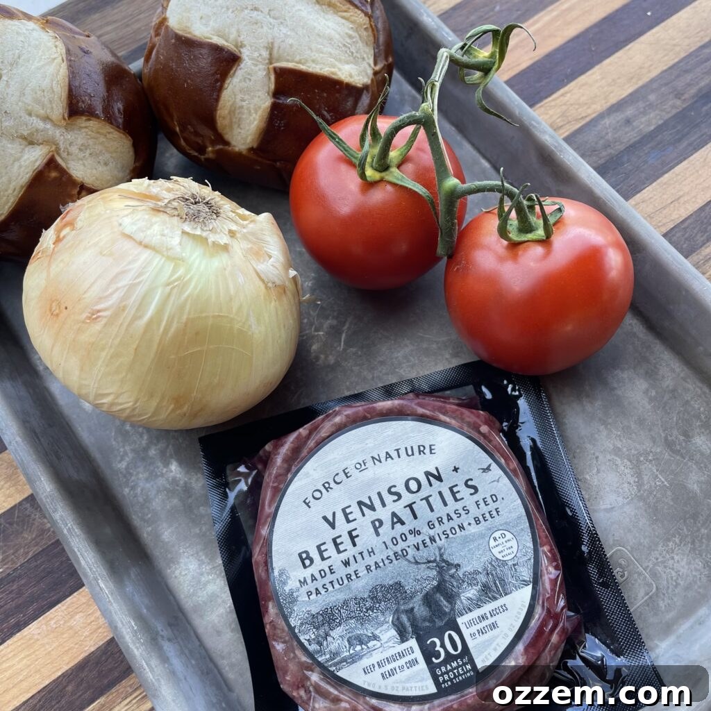 A vibrant display of fresh ingredients for a venison beef burger, including ground venison and beef, white onions, Colby Jack cheese, pretzel buns, ripe tomatoes, and crisp romaine lettuce.