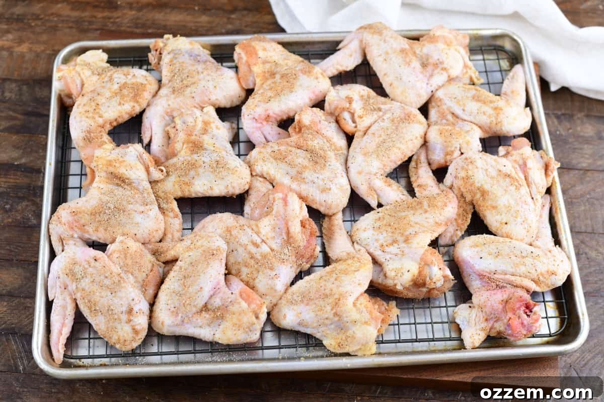 raw wings seasoned on a sheet tray before being placed into the smoker.