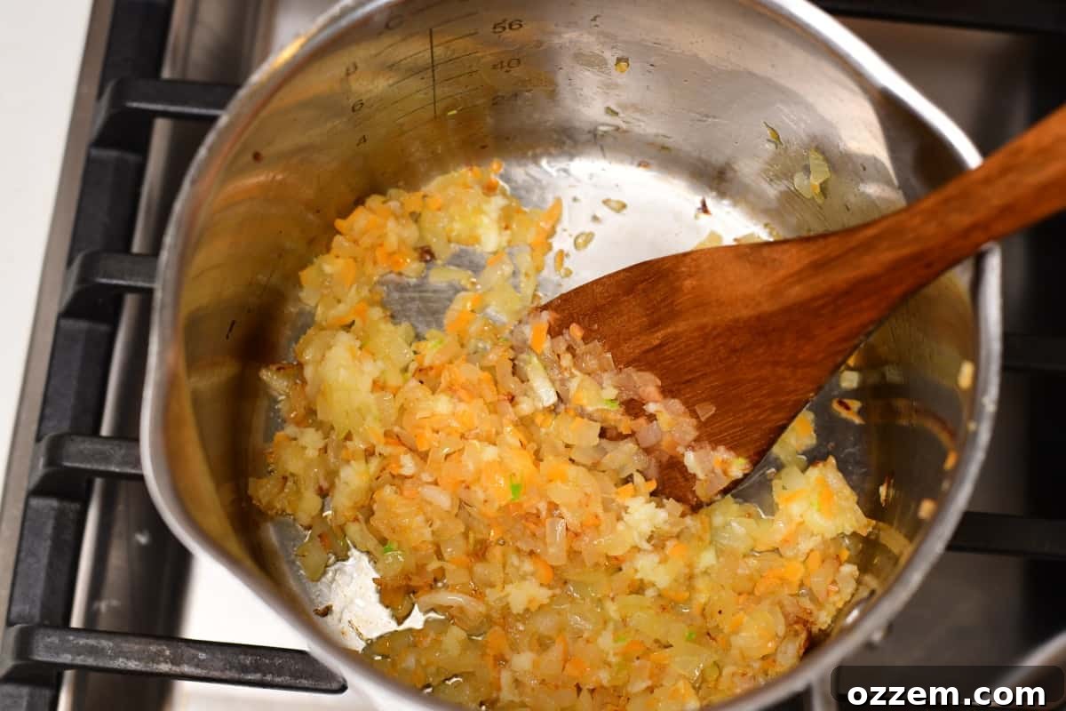 Onion, garlic and peppers being cooked for sauce in a medium sauce pan.