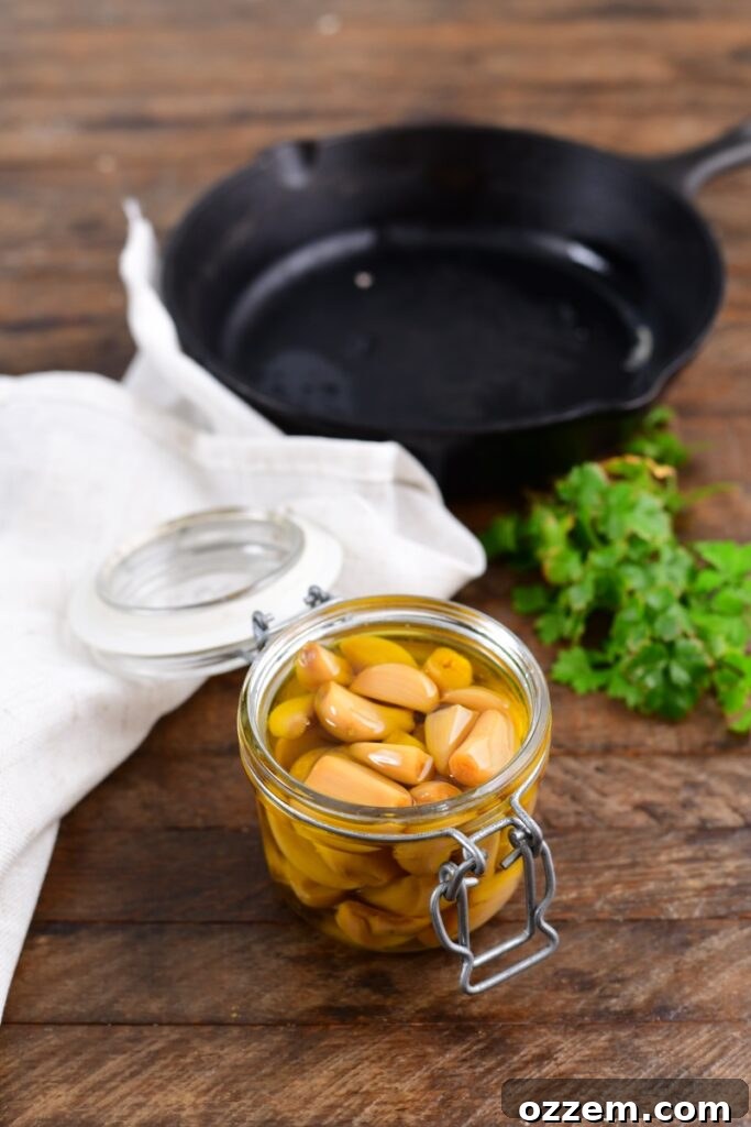 Smoked Roasted Garlic cloves submerged in olive oil in a glass jar.