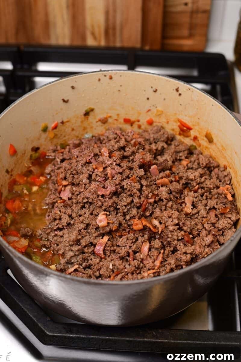 Cooked beef placed on top of cooked bacon in a pot.
