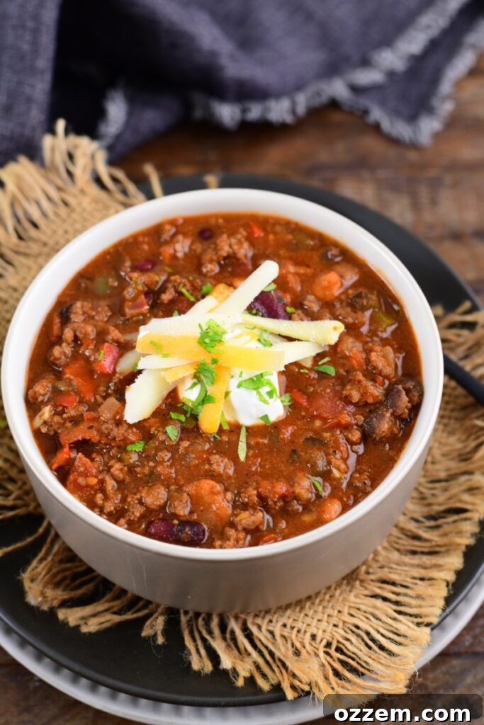 Smoked chili in a white bowl topped with sour cream and cheese