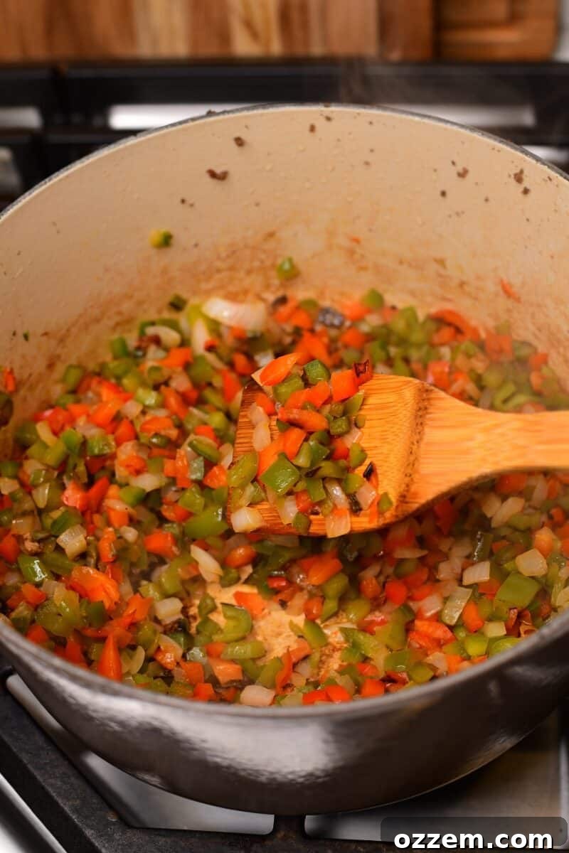 Peppers and onions cooked in pot held in spoon above.