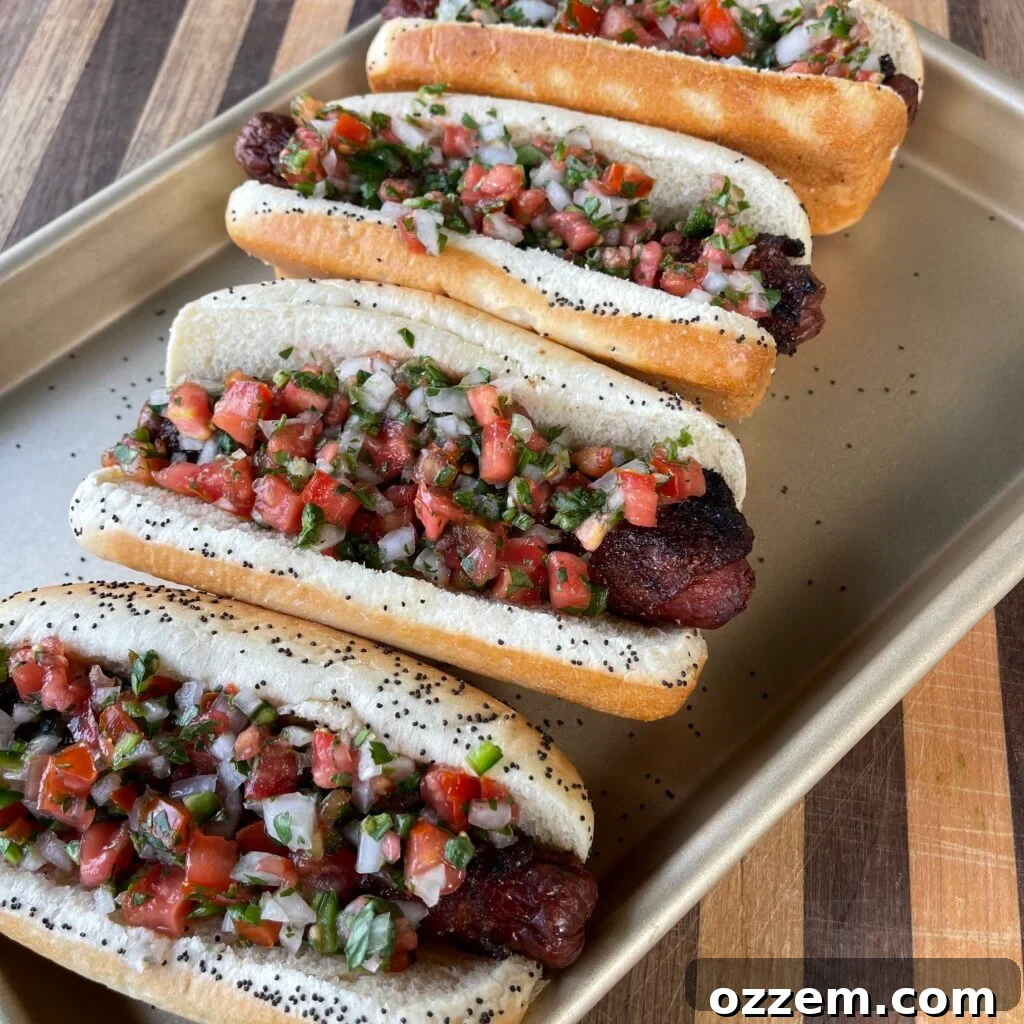 Crispy bacon-wrapped hot dogs topped with fresh pico de gallo, ready for game day celebrations.