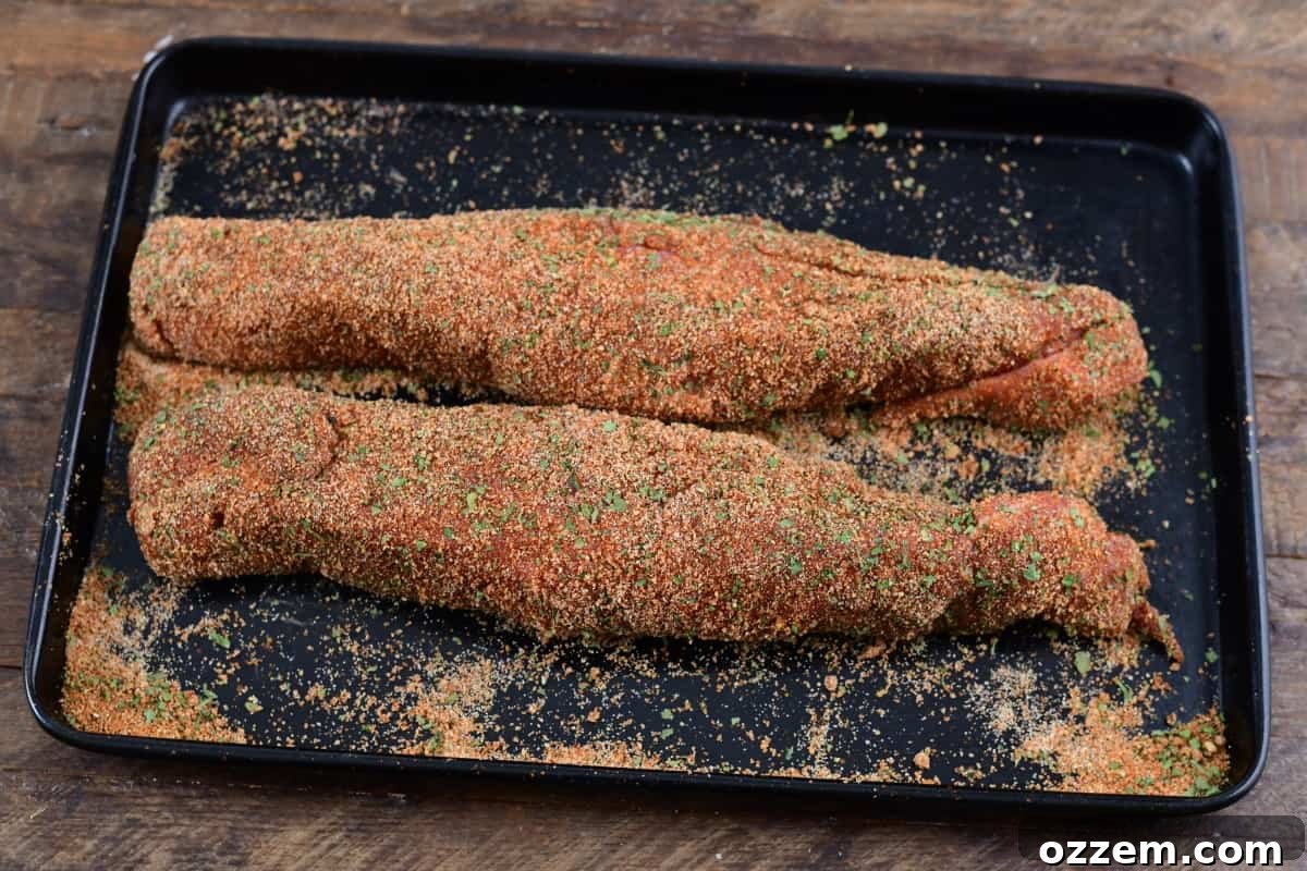Slow-Smoked Pork Perfection 7 2 raw pork tenderloins on sheet tray covered in dry rub