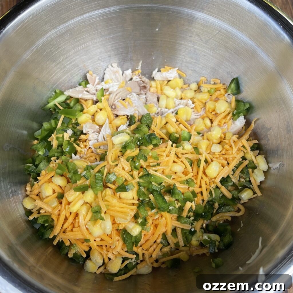 Shredded rotisserie chicken mixed with corn, cheese, and jalapeños, ready for the sauce.